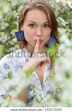 Portrait of pretty blond woman showing gesture to be quiet