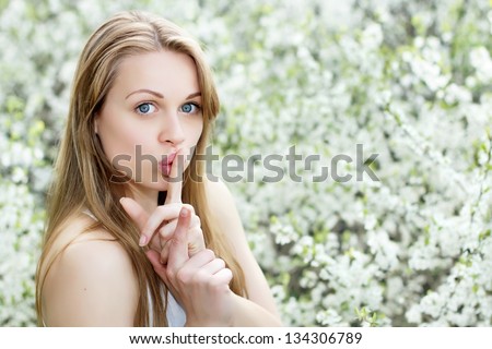 Portrait of young blonde showing gesture to be quiet