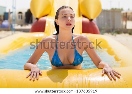 Attractive young brunette posing on the yellow swimming pool