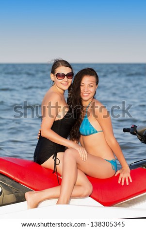 Two young smiling women posing on a water bike