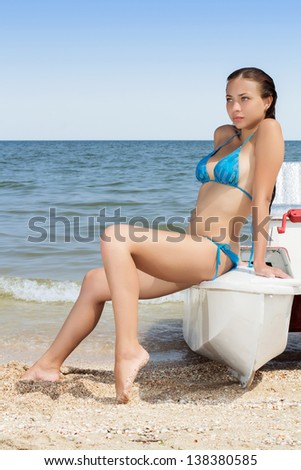 Pretty young woman wearing blue swimsuit posing on the catamaran