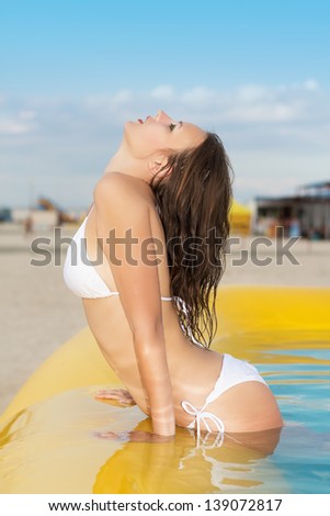 Young sexy woman showing her fit figure in the yellow pool