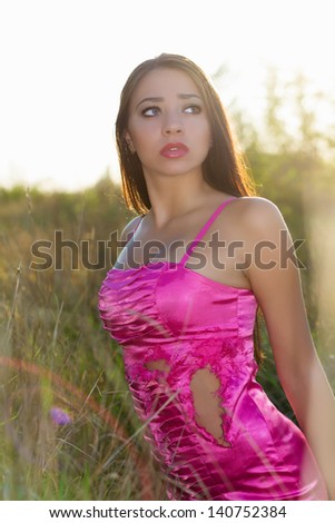 Young frightened brunette wearing torn pink dress