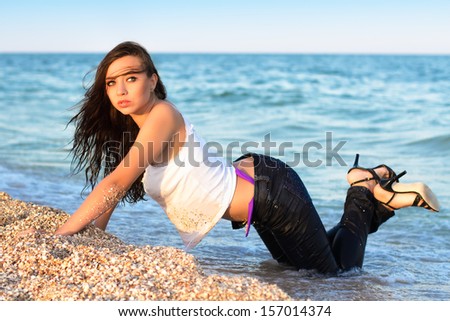 Sexy young woman in jeans posing on the beach