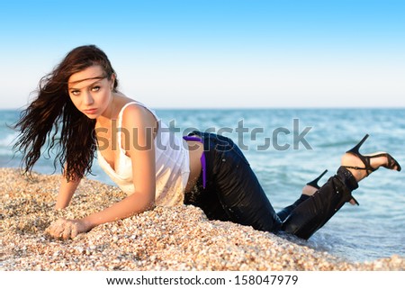 Pretty woman posing in wet clothes on the beach