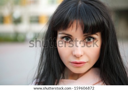 Portrait of attractive brunette with mysterious eyes posing outdoors