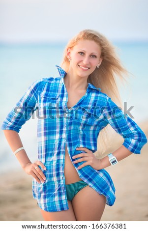 Pretty blond woman in blue blouse posing on the beach