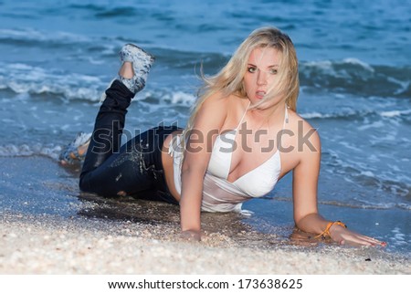 Sexy young woman in wet clothes posing on the beach
