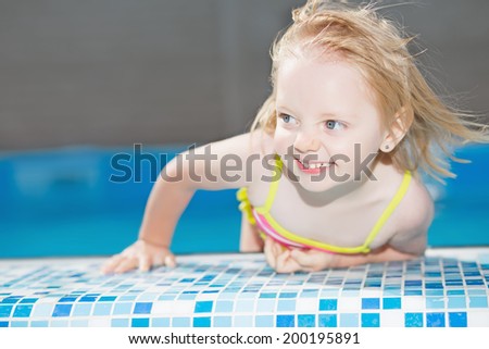 Funny little blond girl posing in water pool