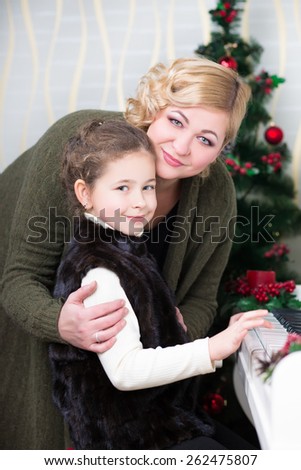 Portrait of smiling woman and a little girl posing near piano