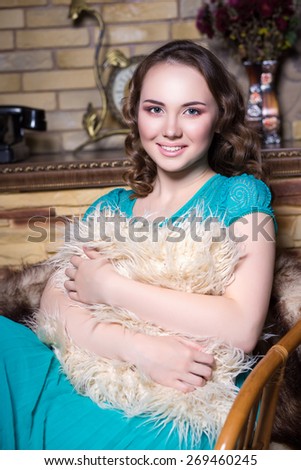 Portrait of smiling woman in turquoise dress sitting on the chair