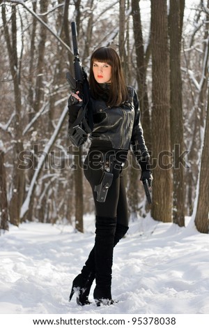 Strong young woman with a rifle in forest