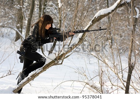 Young woman with a sniper rifle in winter forest
