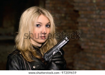 Scared beautiful woman with a gun in abandoned house