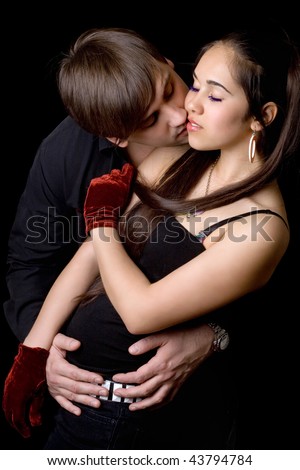 Young man kissing pretty woman. Isolated on black