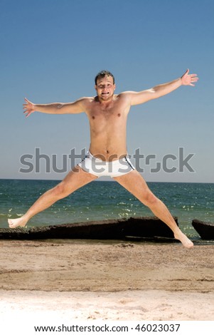 Bizarre young man jumping on a beach
