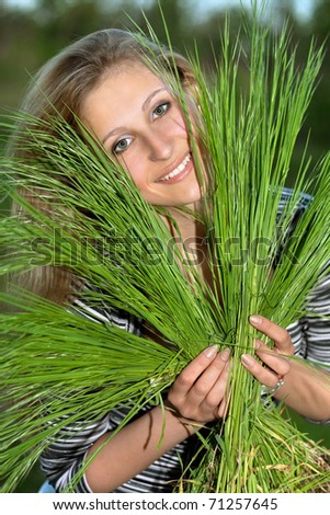 Cheerful blonde with green grass in their hands