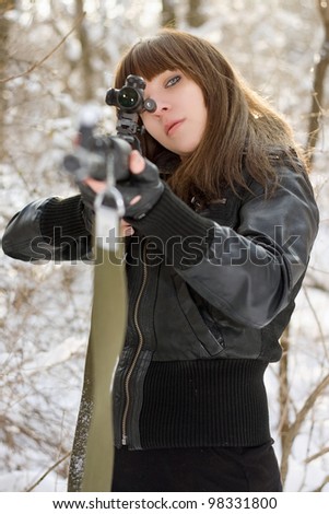 Brunette aiming a gun in the forest