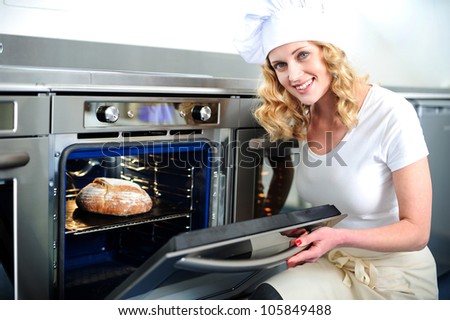 Pretty baker opening an oven door. Ready to pull out baked bread