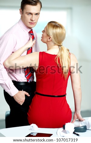 Female secretary feeling naughty. Holding man\'s tie and looking into his eyes