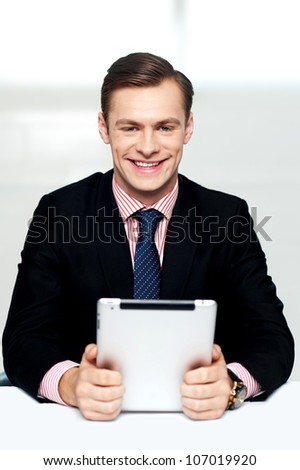 Cheerful male executive holding touch screen enabled digital device