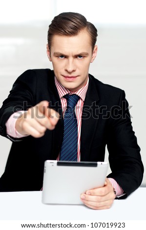Tech savvy corporate man pointing at you. Serious look on face