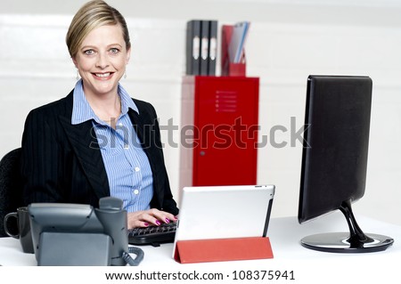 Cheerful female secretary typing document on computer. Working in office