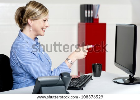 Businesswoman pointing at computer screen seated in office