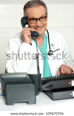 Happy aged medical expert taking on phone wearing glasses