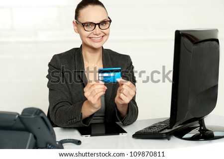 Smiling corporate lady in her office showing credit card to camera