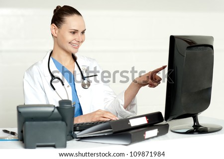 Female medical expert pointing at computer screen sitting in her lab