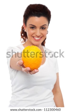 Smiling beautiful woman offering you an orange. Eat healthy, stay fit