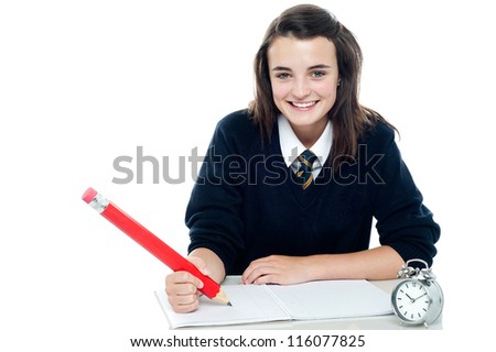 Profile shot of smiling school girl taking down notes, holding big red pencil