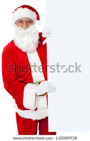 Aged Santa holding blank white banner ad board. Standing beside