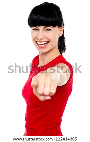 Attractive woman pointing at you and flashing a smile.