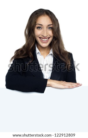 Female executive behind blank white ad board, business concept.