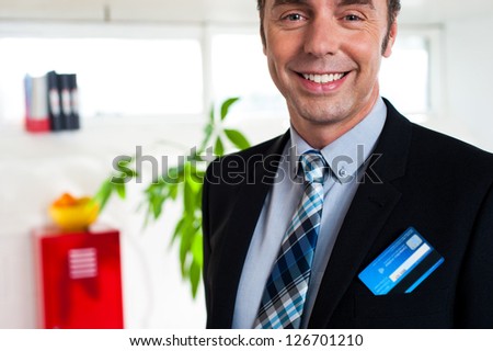 Cropped image of smiling young entrepreneur with credit card popping out of his blazer pocket.