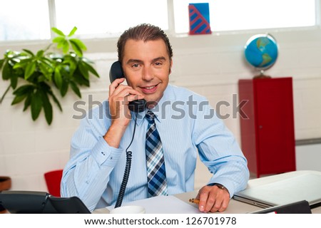 Smart looking smiling male executive on a call.