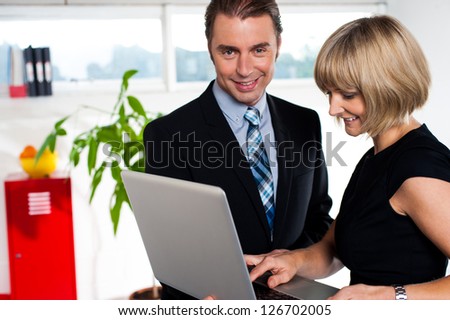 Boss and secretary discussing power point presentation saved on laptop.