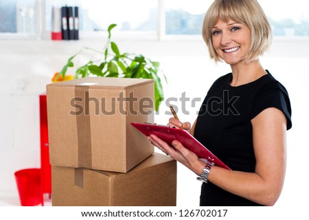 Smiling woman with a clipboard in hand matching list of items after successful relocation.