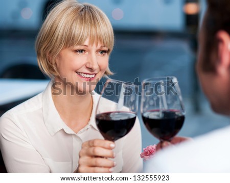 Gorgeous middle aged woman looking at her man with love and toasting wine.