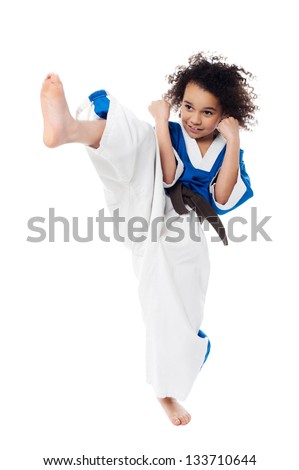 Young kid kicking in the air while practicing karate.