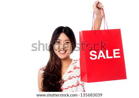 Young trendy girl holding up shopping bag. Year end sale begins.