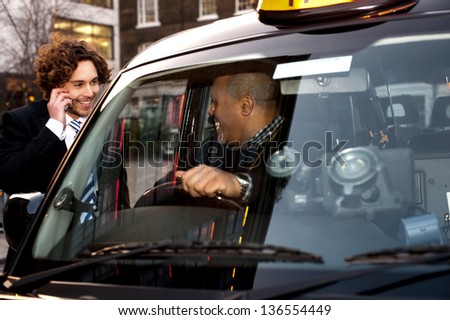 Taxi cab driver communicating with male passenger.