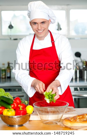 Smiling male chef cutting vegetables