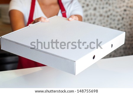 Woman handing over pizza, cropped image.