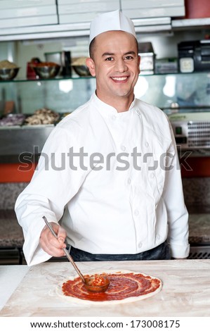 Cheerful chef preparing the pizza base