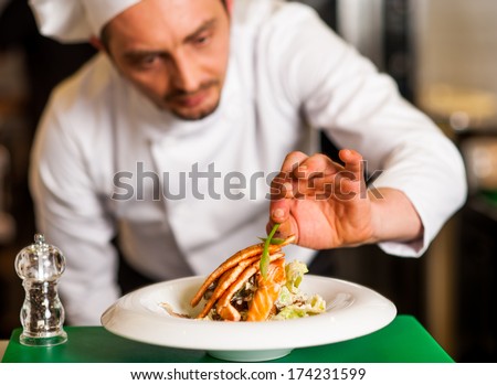 Chef adding final touch to delicious baked salmon Chef adding final touch to delicious baked salmon