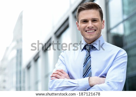 Smiling corporate guy posing with arms crossed