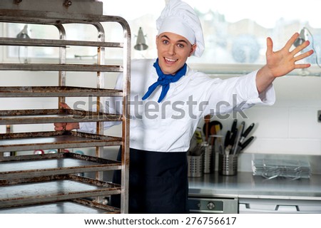 Male chef in kitchen holding food tray rack